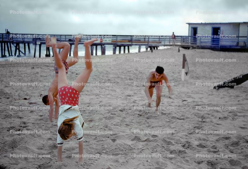 Girl and boys, handstand, beach, 1960s