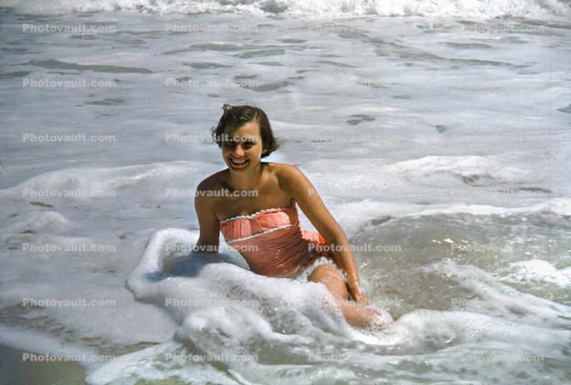 Smiling lasdy at the beach, waves, 1950s