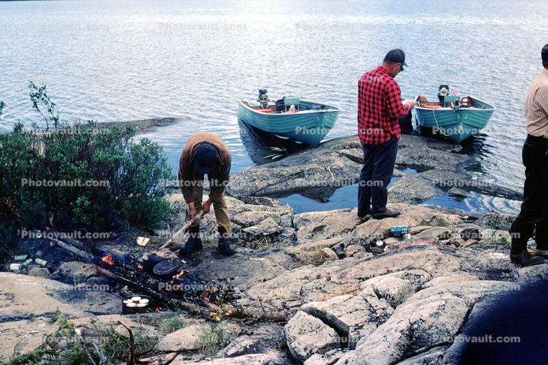 Wilderness cooking, Camp Fire, lake, powerboats, rocks, shore, Manitoba, Canada, 1970, 1970s