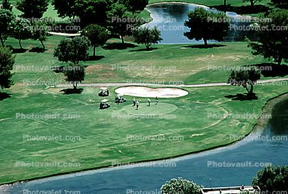 golf course, putting green, golf carts, lake, pond, water hazard, trees