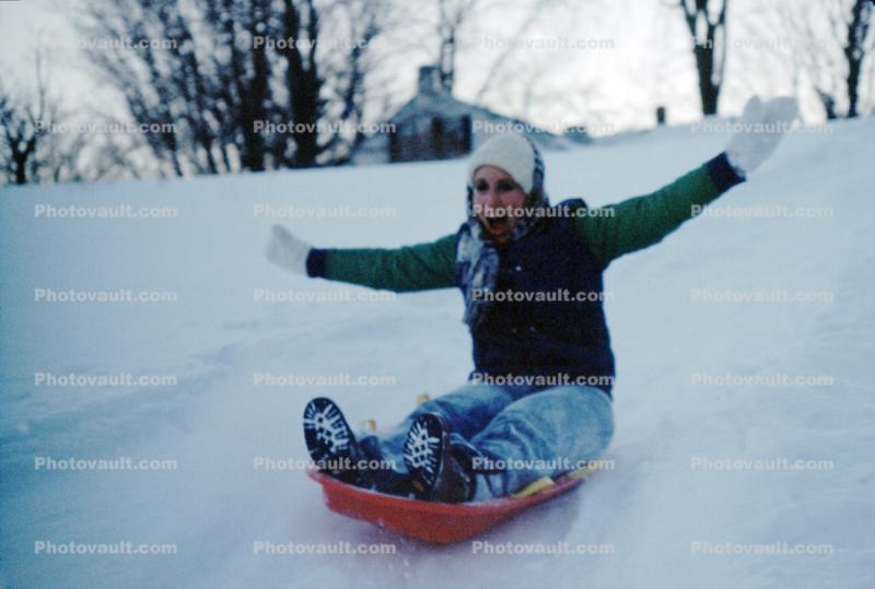 Girl Sliding down a hill in the Snow, smiles, mittens