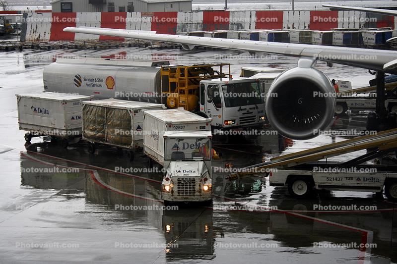 LaGuardia Airport (LGA), Boeing 757, Shell refueling truck, carts, belt loader, Baggage Tractors, rain, rainy, inclement weather, precipitation