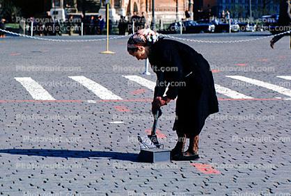 Woman sweeper, sweeping, cobblestone street, crosswalk
