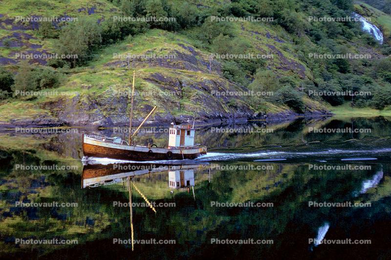 Small fishing trawler on a calm reflective Fjord