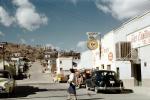 Woman crossing the street, Cars, shops, stores, Homes on a hill, houses, buildings, 1950s, CBMV06P02_18