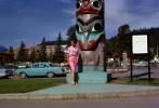 Woman Poses in front of a Totem Pole, cars, 1950s, CNAV03P02_18