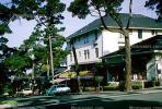 Stores, cypress trees, cars, building, downtown Carmel, 1960s, CNCV01P01_01