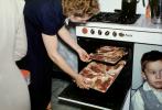 Woman puts meat into the oven, Stove, boy, 1950s, FDNV03P03_14