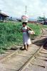 Woman walking along railroad tracks