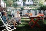 Women, backyard, chairs, bench, picnic table, picket fence, 1940s