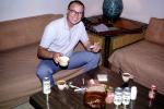 Man, Smiling, sofa, couch, eathing, coors beer cans, table, cup, glasses