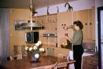Woman pours a drink, television, lamp, table, flowers, den, wetbar, 1960s