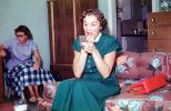 Primping housewife, putting on lipstick, make-up, purse, sofa, 1950s