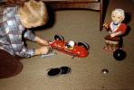 Boy with Fire Bird Toy Race Car fixing tires, 1950s