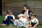 Woman with her sons, swaddled baby, floral dress, Easter Basket, smiles, 1950s