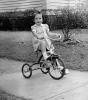 Tricycle, Girl, formal dress, sidewalk, 1950s