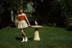 Girl in the Backyard, skirt, grass, lawn, birdbath, 1950s, PMCV04P03_02