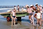 Lifeguards pushing boat into the water, 1950s