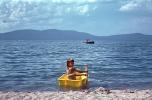Girl on a tiny rowboat, paddle, beach, sand, Lake Tahoe, 1960s