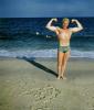 Muscle Beach, Man flexing muscles, water, sand, suntan, 1950s