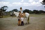 Girl on a horse, boy, smiles, 1950s