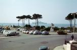 Cars in a parking lot, trees, ship, statue, 1950s